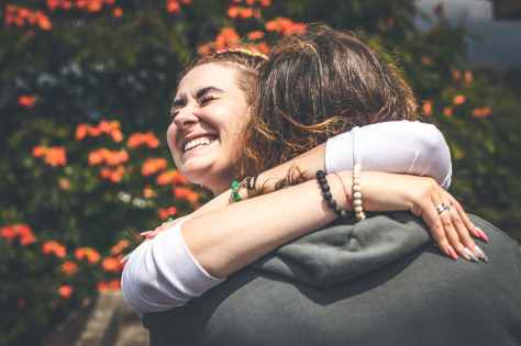 smiling woman hugging another person