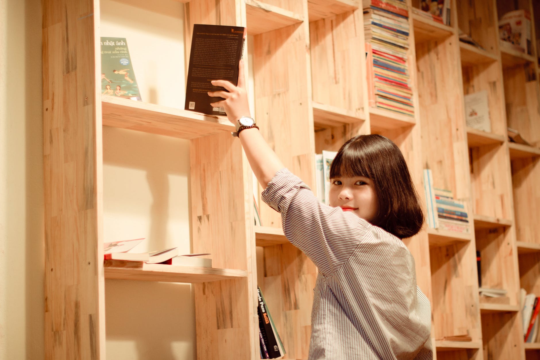 woman standing beside book shelf