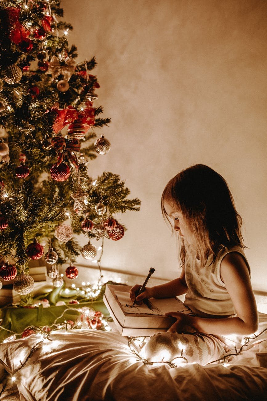photo of girl sitting near christmas tree