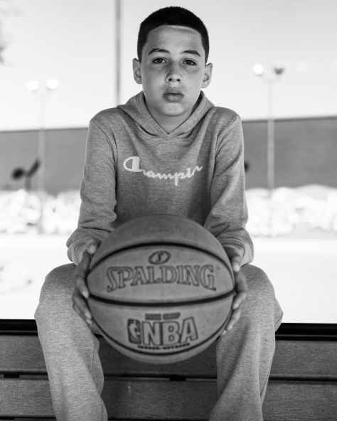 a boy seated holding a basket ball